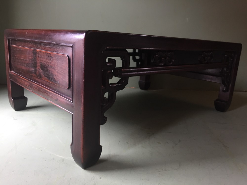 A late 19th-century Chinese dark hongmu hardwood scholars low table featuring carved cloud motif spandrels and straight legs. View X
