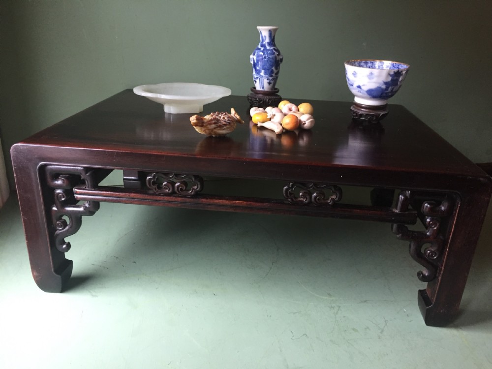 A late 19th-century Chinese dark hongmu hardwood scholars low table featuring carved cloud motif spandrels and straight legs. View XIX