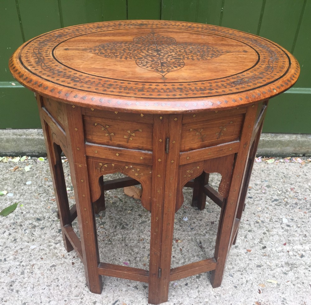 Late C19th Indian brass-inlaid oval teak occasional table on folding arcaded base.