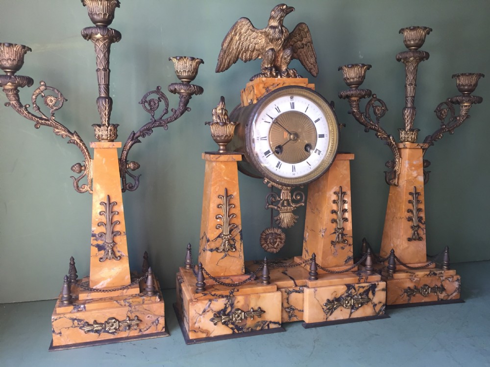 A late nineteenth-century French Empire style clock garniture crafted from yellow Siena marble and gilt ormolu, featuring a central clock topped with an eagle and flanked by two candelabra. View II