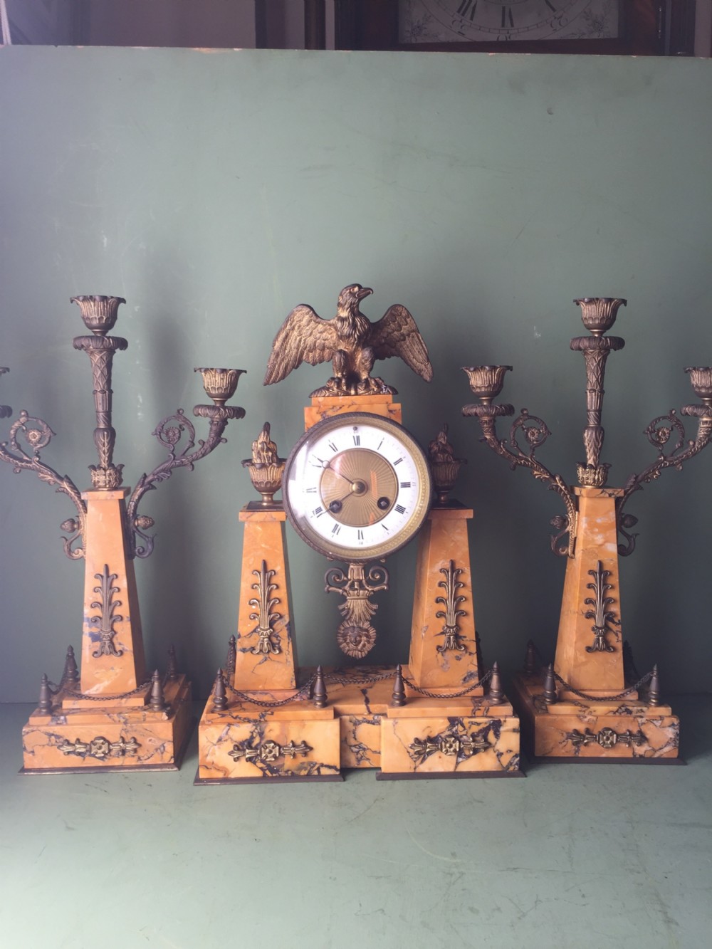 A late nineteenth-century French Empire style clock garniture crafted from yellow Siena marble and gilt ormolu, featuring a central clock topped with an eagle and flanked by two candelabra. View VI