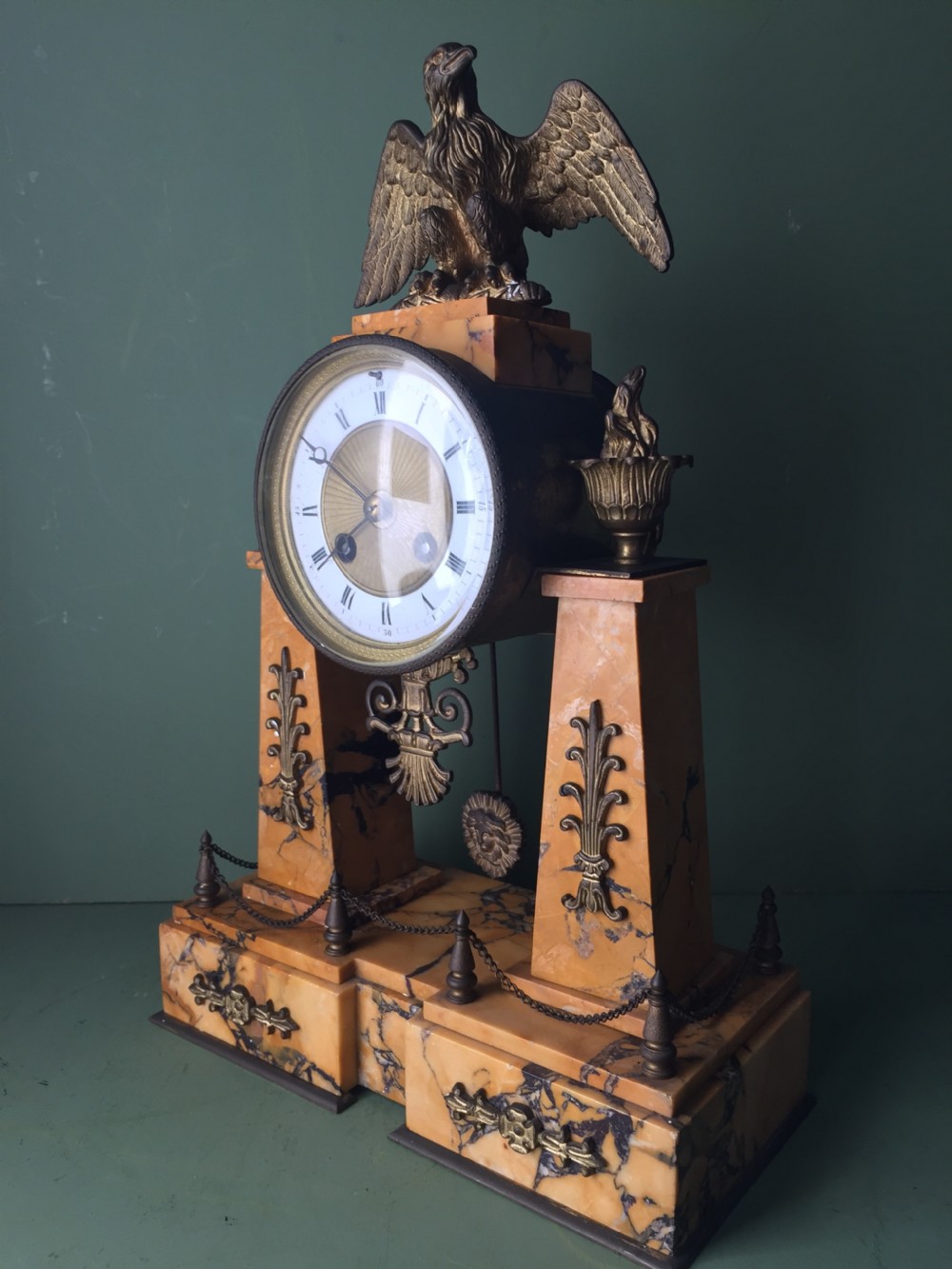 A late nineteenth-century French Empire style clock garniture crafted from yellow Siena marble and gilt ormolu, featuring a central clock topped with an eagle and flanked by two candelabra. View X