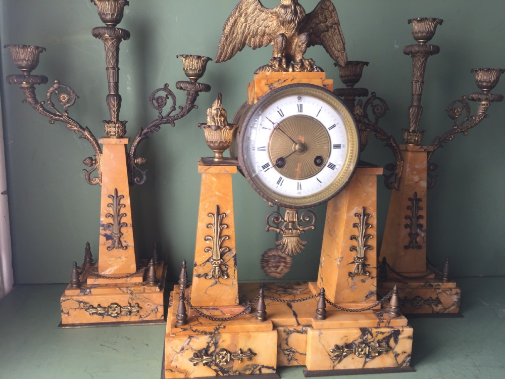 A late nineteenth-century French Empire style clock garniture crafted from yellow Siena marble and gilt ormolu, featuring a central clock topped with an eagle and flanked by two candelabra. View XIV
