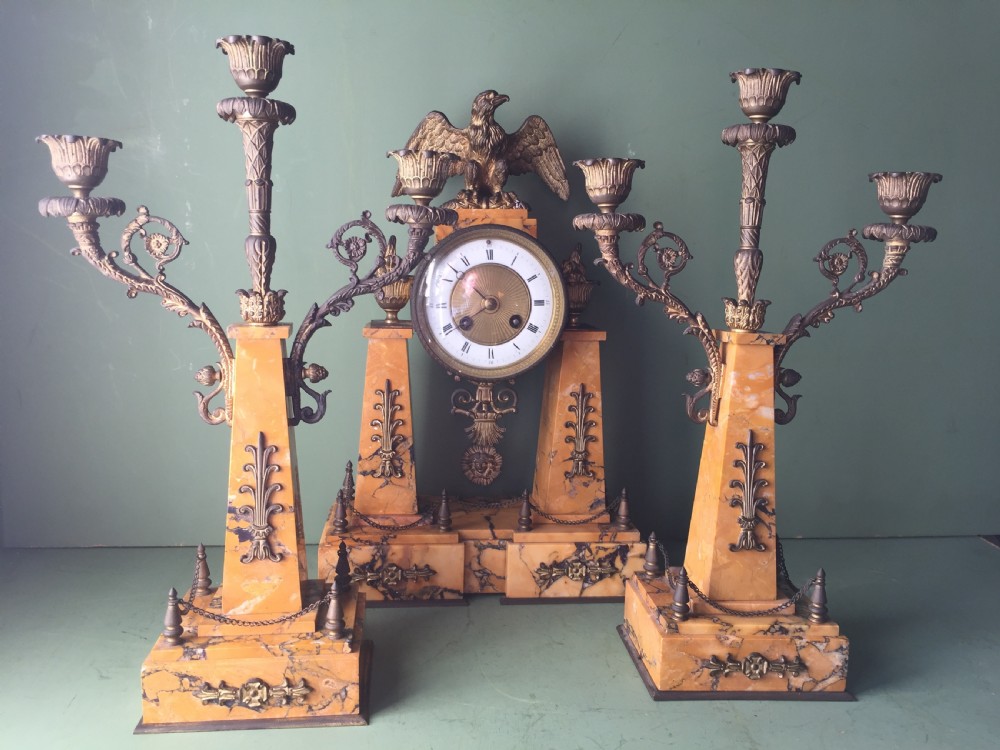 A late nineteenth-century French Empire style clock garniture crafted from yellow Siena marble and gilt ormolu, featuring a central clock topped with an eagle and flanked by two candelabra. View XXII