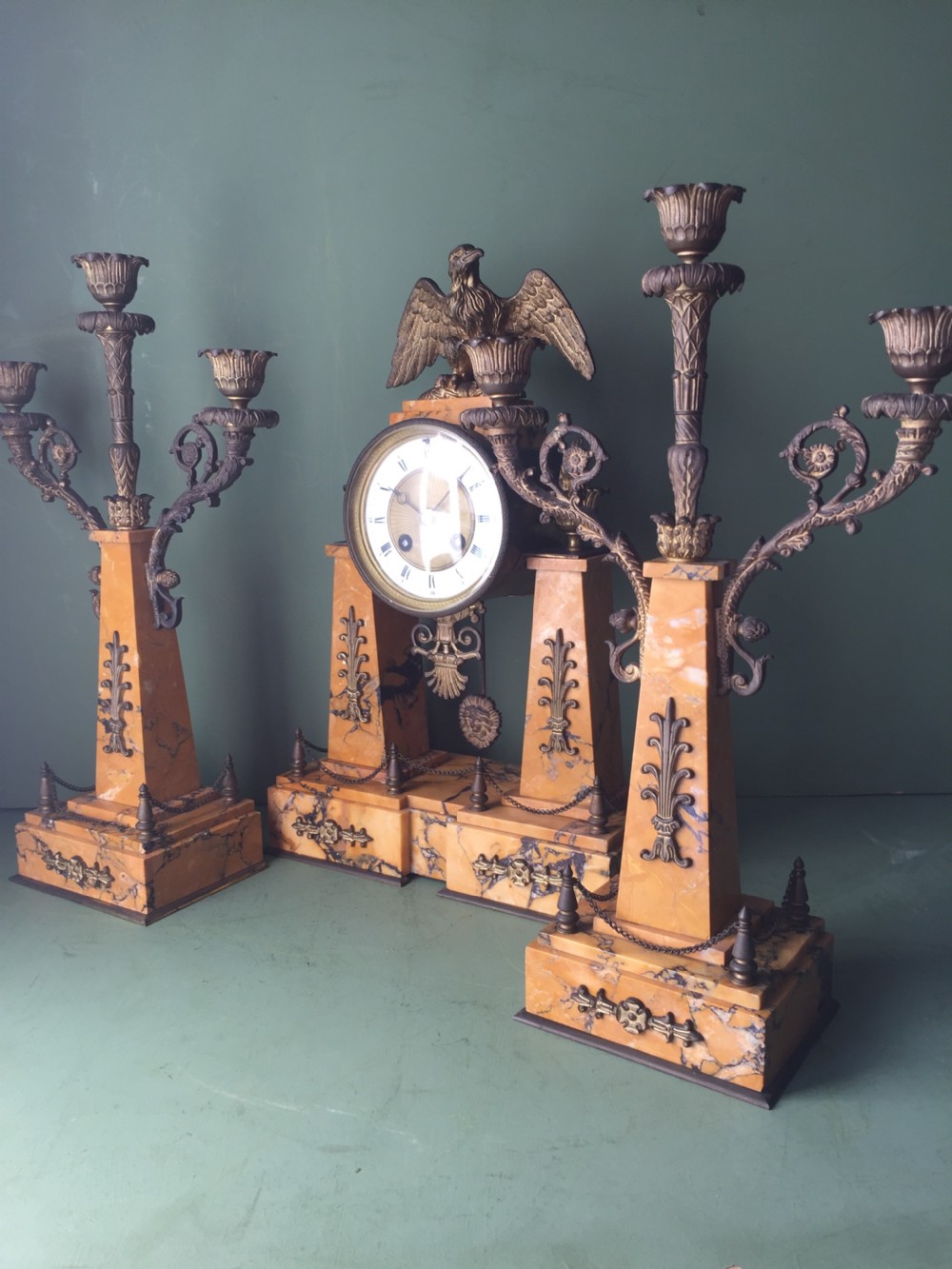 A late nineteenth-century French Empire style clock garniture crafted from yellow Siena marble and gilt ormolu, featuring a central clock topped with an eagle and flanked by two candelabra. View XXIX