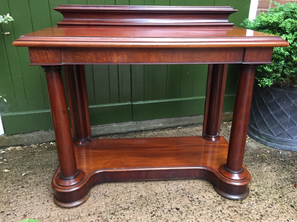 A William IV mahogany hall console table with cylindrical column supports, a raised rear gallery, and a lower plinth shelf. View II