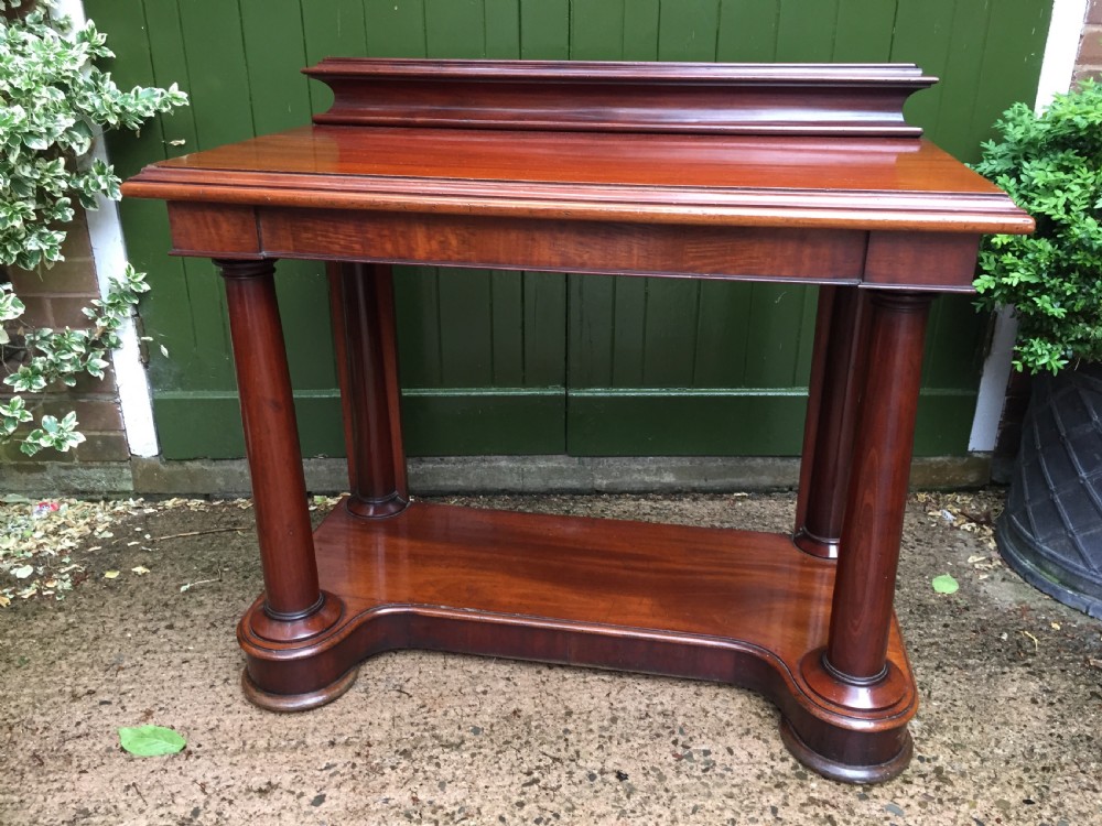 A William IV mahogany hall console table with cylindrical column supports, a raised rear gallery, and a lower plinth shelf. View V
