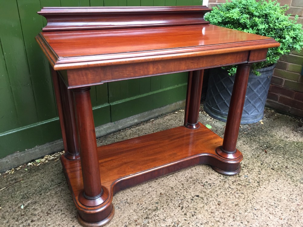 A William IV mahogany hall console table with cylindrical column supports, a raised rear gallery, and a lower plinth shelf. View VI