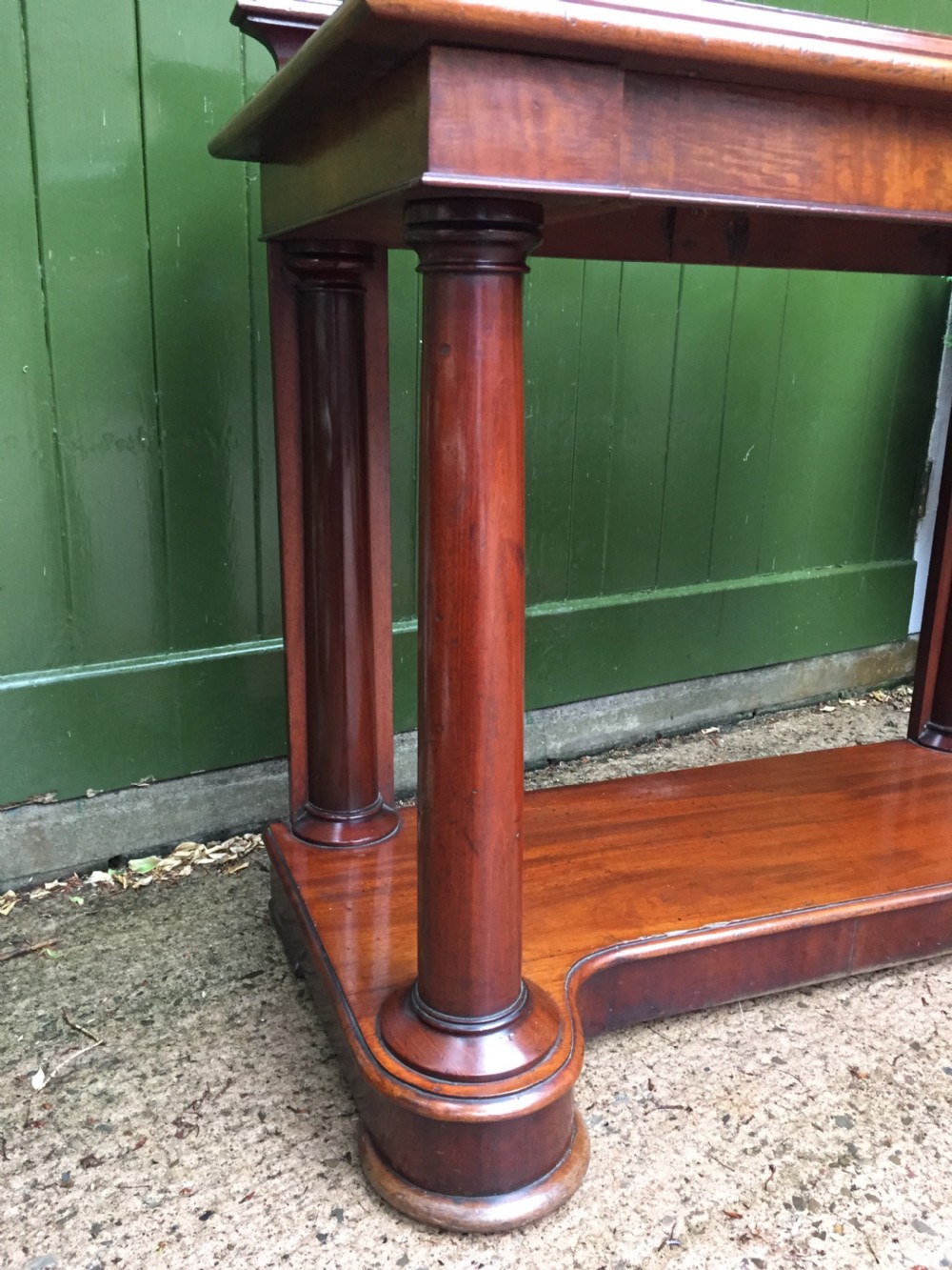 A William IV mahogany hall console table with cylindrical column supports, a raised rear gallery, and a lower plinth shelf. View VII