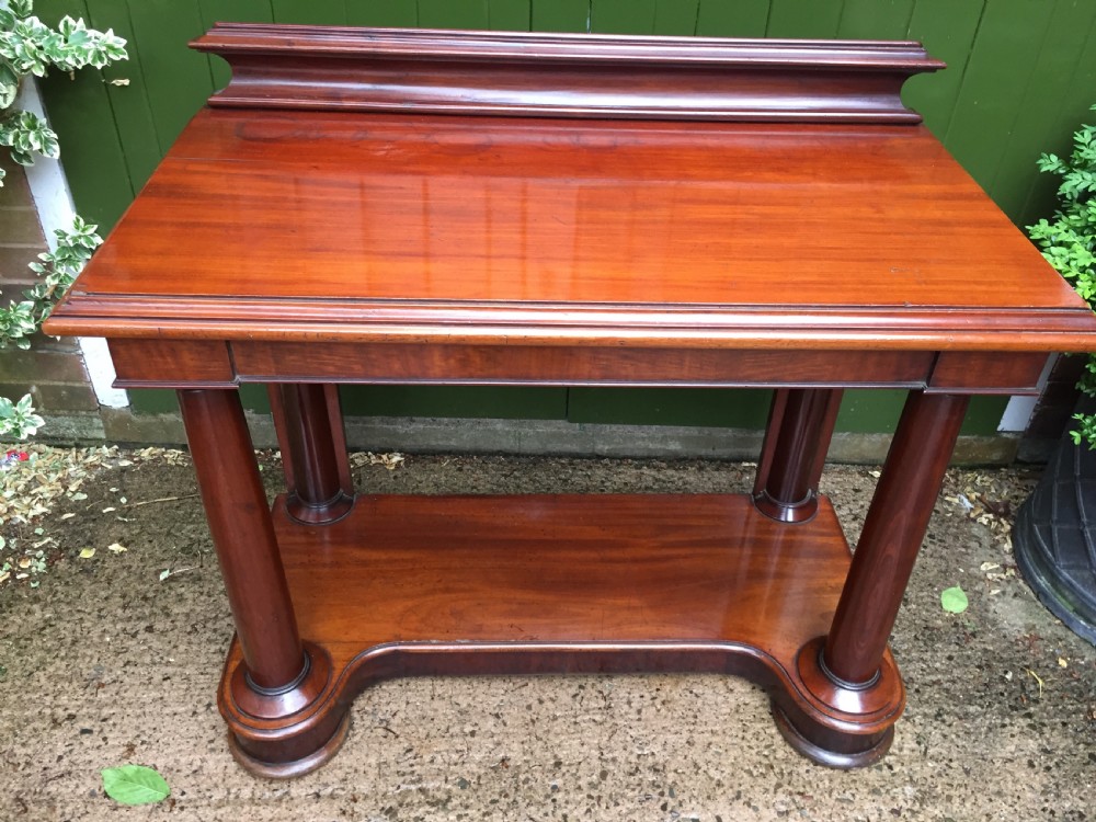 A William IV mahogany hall console table with cylindrical column supports, a raised rear gallery, and a lower plinth shelf. View XII