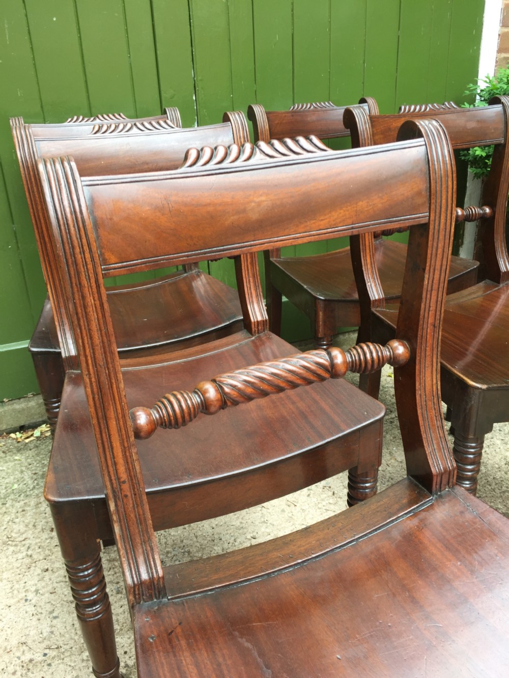 A set of six early nineteenth-century mahogany dining chairs featuring carved top rails, rope twist splats, solid wooden seats, and turned front legs. View VI
