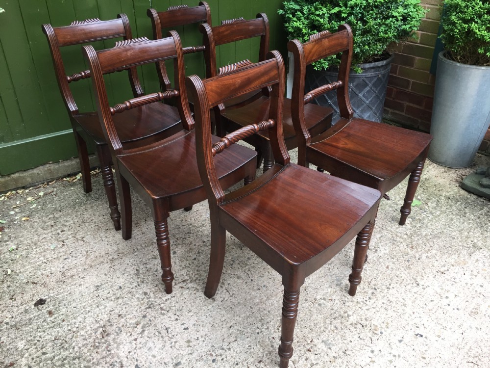 A set of six early nineteenth-century mahogany dining chairs featuring carved top rails, rope twist splats, solid wooden seats, and turned front legs. View XIV