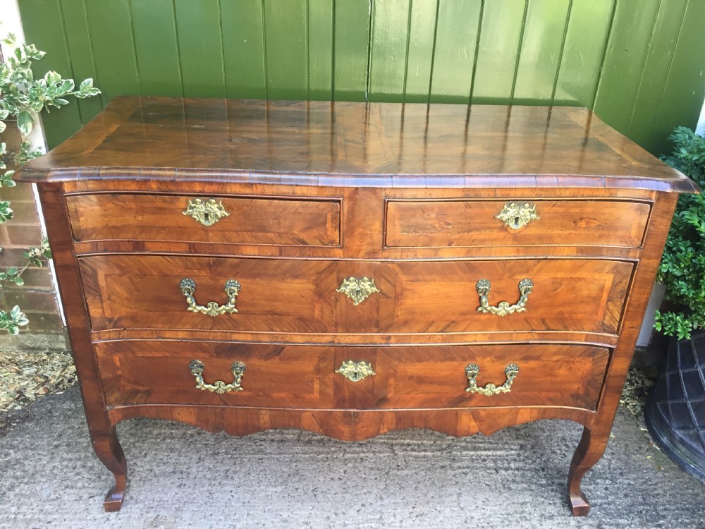 A mid-18th-century Italian serpentine commode with parquetry olive wood and walnut veneers and ornate brass mounts. View V