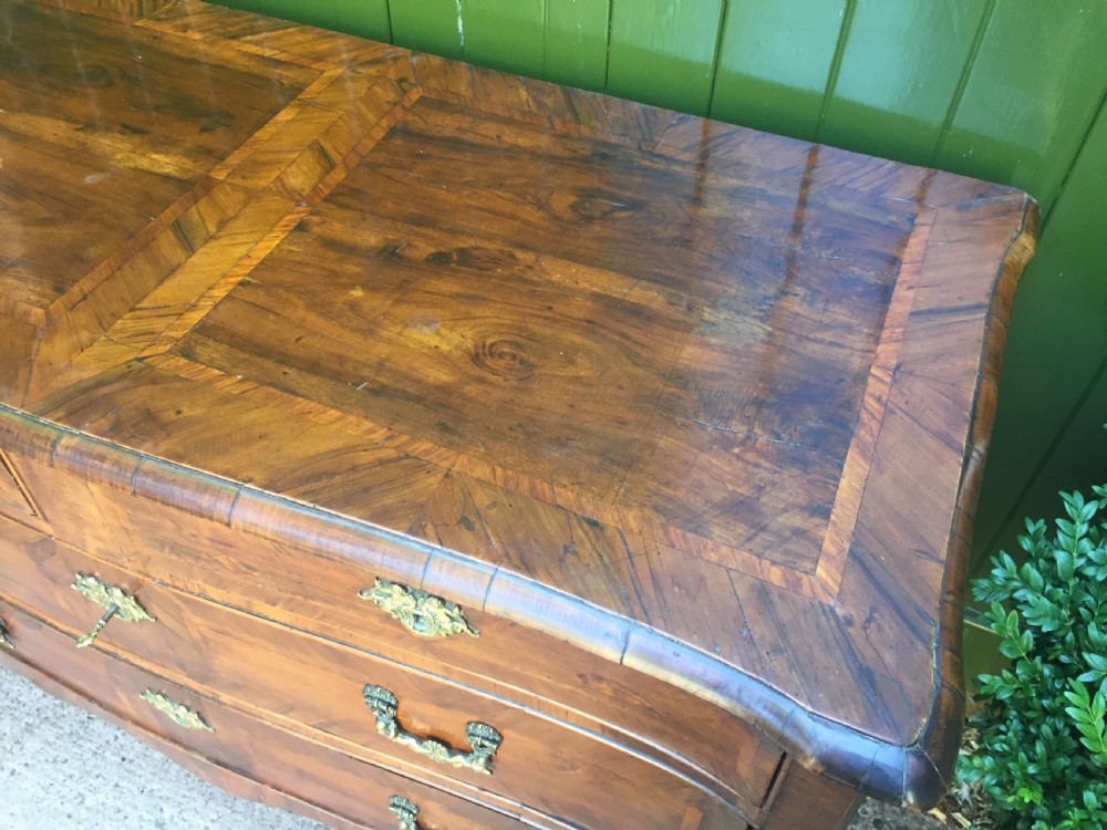 A mid-18th-century Italian serpentine commode with parquetry olive wood and walnut veneers and ornate brass mounts. View VI
