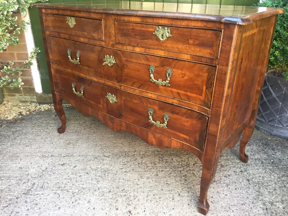A mid-18th-century Italian serpentine commode with parquetry olive wood and walnut veneers and ornate brass mounts. View XV