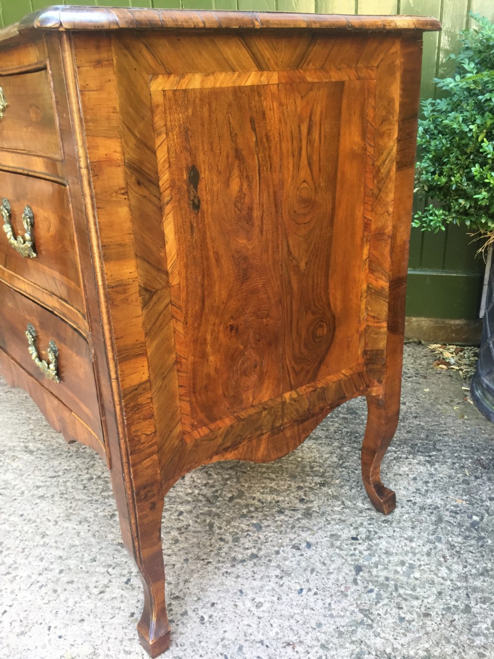 A mid-18th-century Italian serpentine commode with parquetry olive wood and walnut veneers and ornate brass mounts. View XVI
