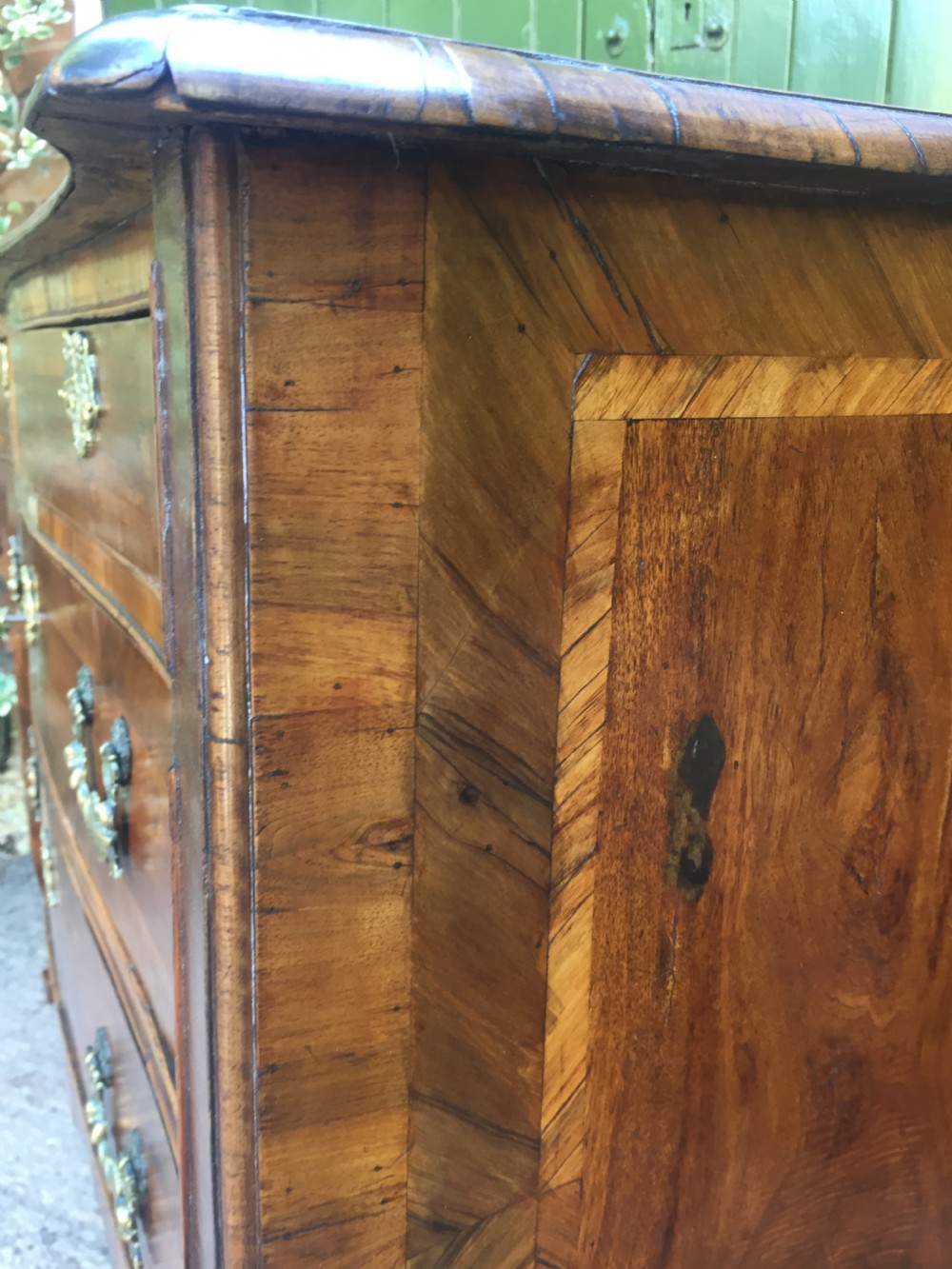 A mid-18th-century Italian serpentine commode with parquetry olive wood and walnut veneers and ornate brass mounts. View XVII
