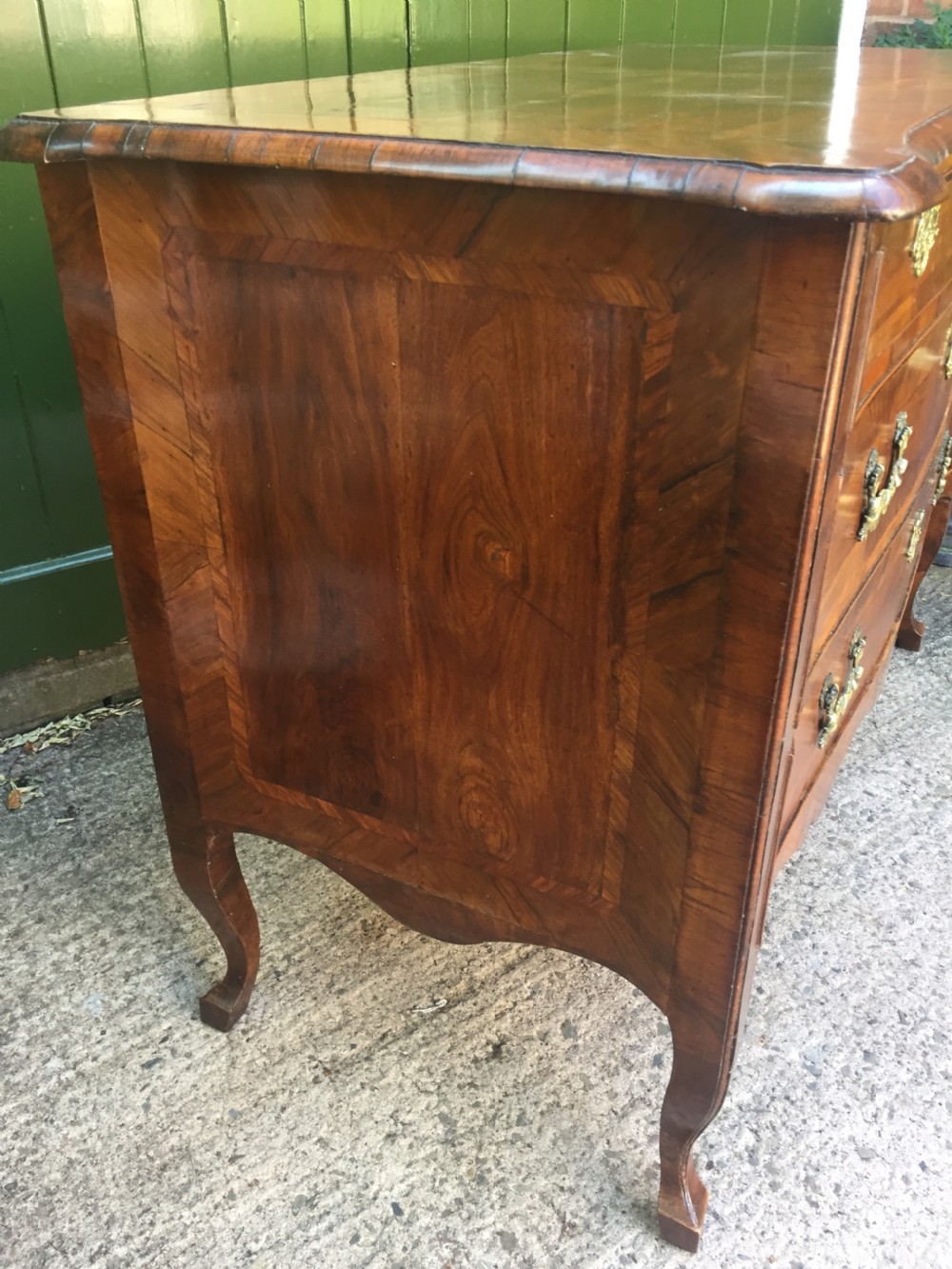 A mid-18th-century Italian serpentine commode with parquetry olive wood and walnut veneers and ornate brass mounts. View XVIII