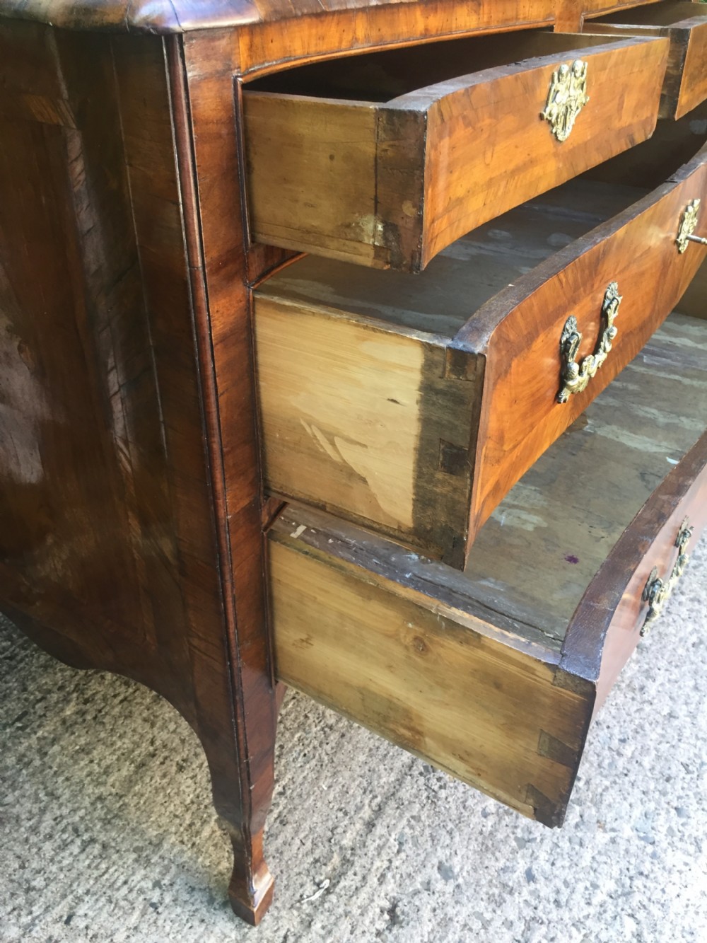 A mid-18th-century Italian serpentine commode with parquetry olive wood and walnut veneers and ornate brass mounts. View XXV
