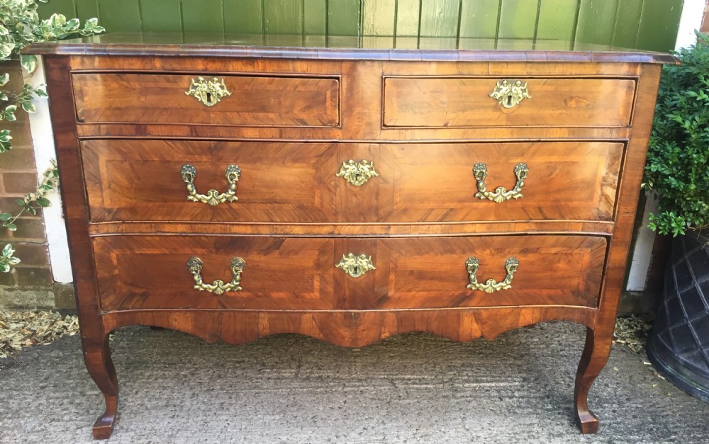 A mid-18th-century Italian serpentine commode with parquetry olive wood and walnut veneers and ornate brass mounts. View XXVII
