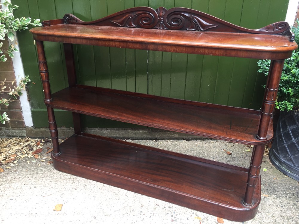 An early 19th-century George IV three-tier mahogany buffet featuring a carved scroll backboard, turned column supports, and a solid plinth base. View II