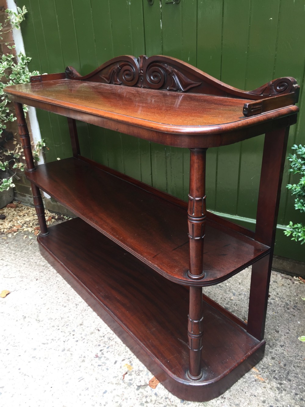 An early 19th-century George IV three-tier mahogany buffet featuring a carved scroll backboard, turned column supports, and a solid plinth base. View V