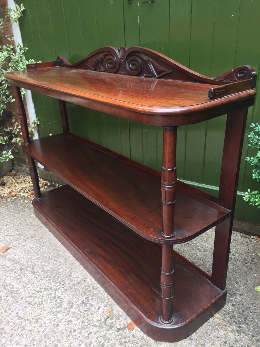An early 19th-century George IV three-tier mahogany buffet featuring a carved scroll backboard, turned column supports, and a solid plinth base. View VI