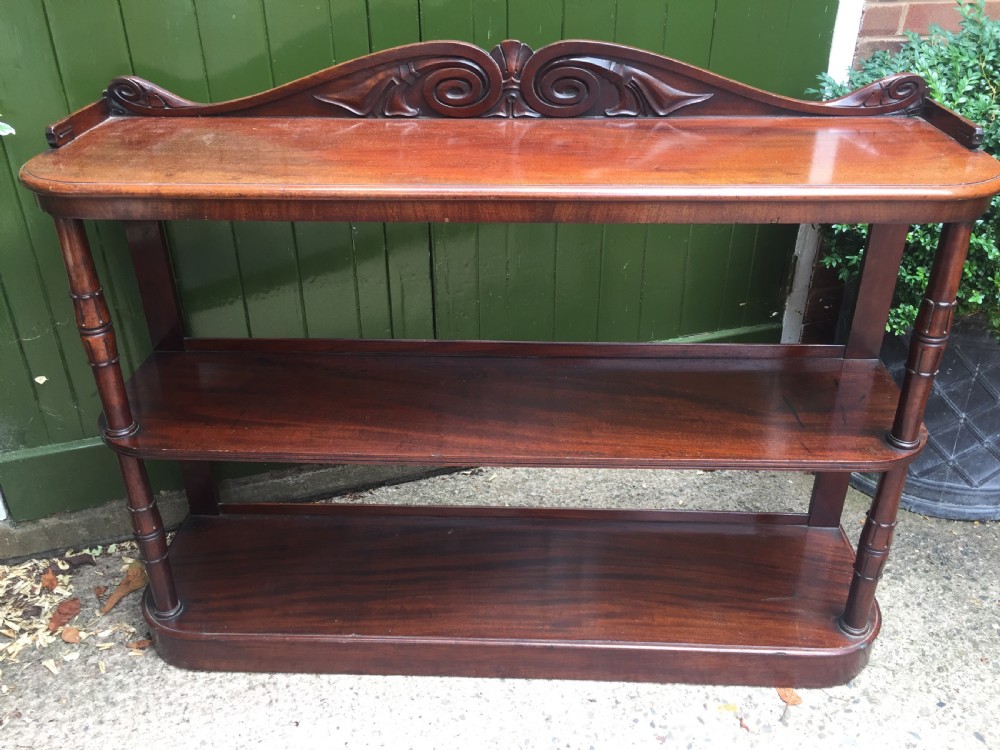 An early 19th-century George IV three-tier mahogany buffet featuring a carved scroll backboard, turned column supports, and a solid plinth base. View VII