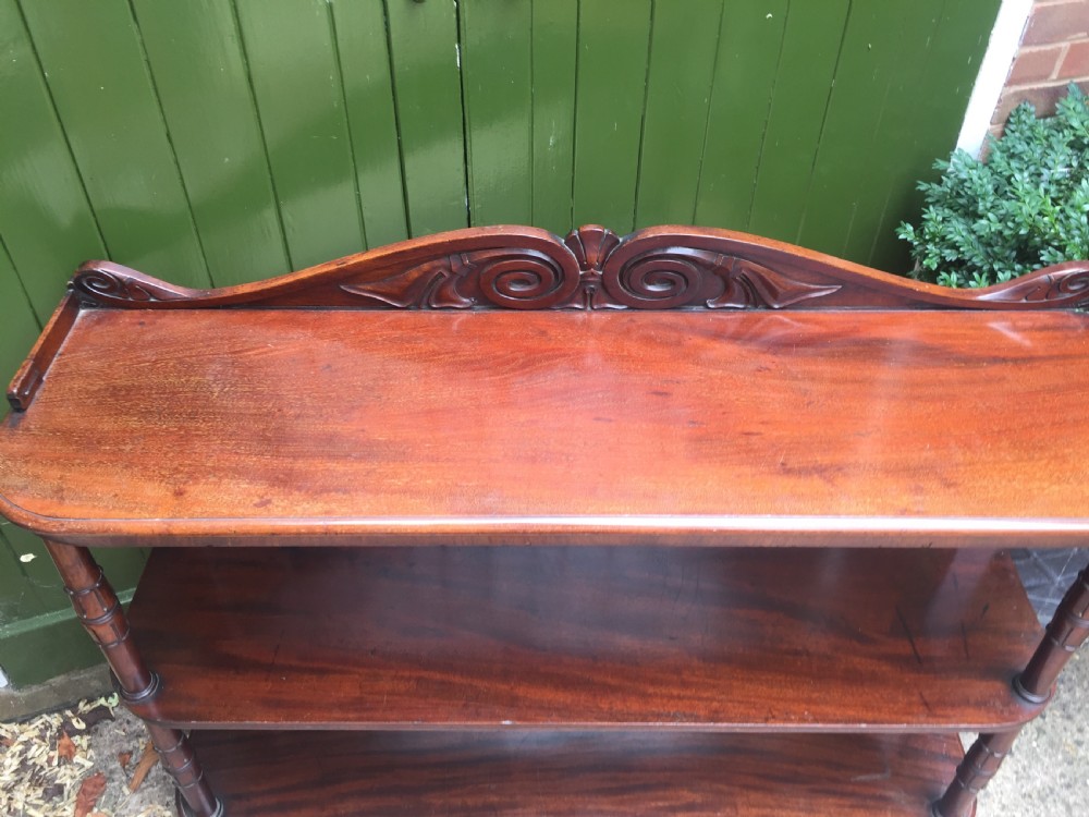 An early 19th-century George IV three-tier mahogany buffet featuring a carved scroll backboard, turned column supports, and a solid plinth base. View VIII