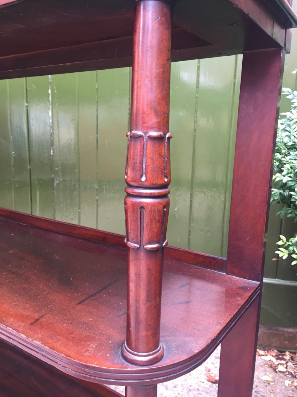 An early 19th-century George IV three-tier mahogany buffet featuring a carved scroll backboard, turned column supports, and a solid plinth base. View IX
