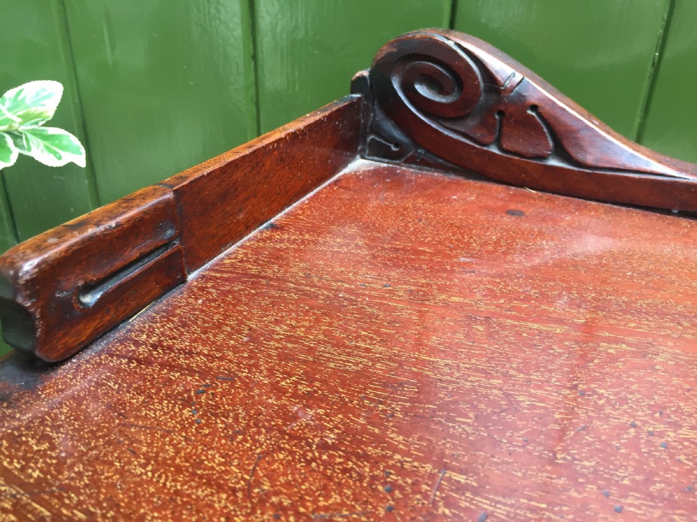 An early 19th-century George IV three-tier mahogany buffet featuring a carved scroll backboard, turned column supports, and a solid plinth base. View X