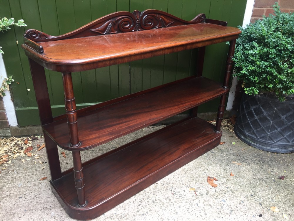 An early 19th-century George IV three-tier mahogany buffet featuring a carved scroll backboard, turned column supports, and a solid plinth base. View XII