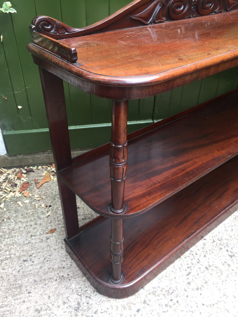 An early 19th-century George IV three-tier mahogany buffet featuring a carved scroll backboard, turned column supports, and a solid plinth base. View XIII