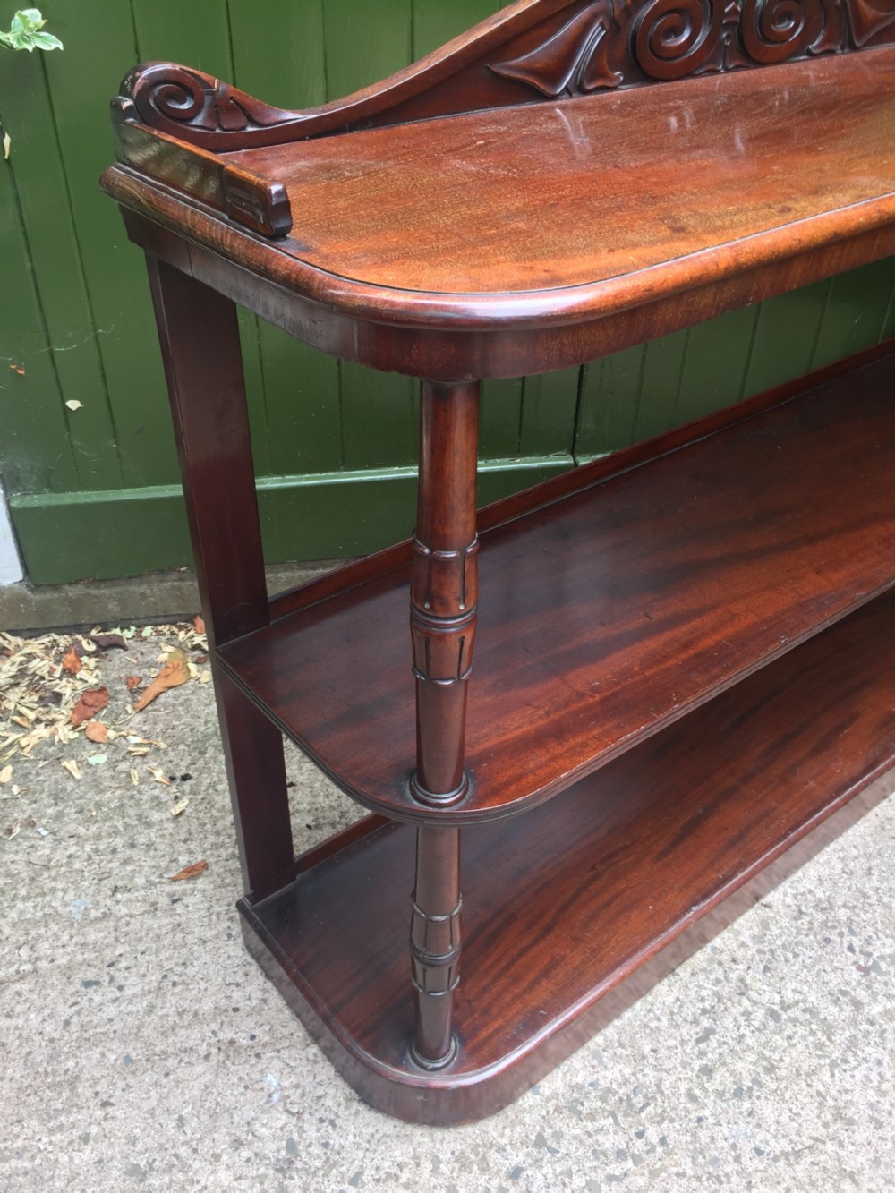 An early 19th-century George IV three-tier mahogany buffet featuring a carved scroll backboard, turned column supports, and a solid plinth base. View XIV