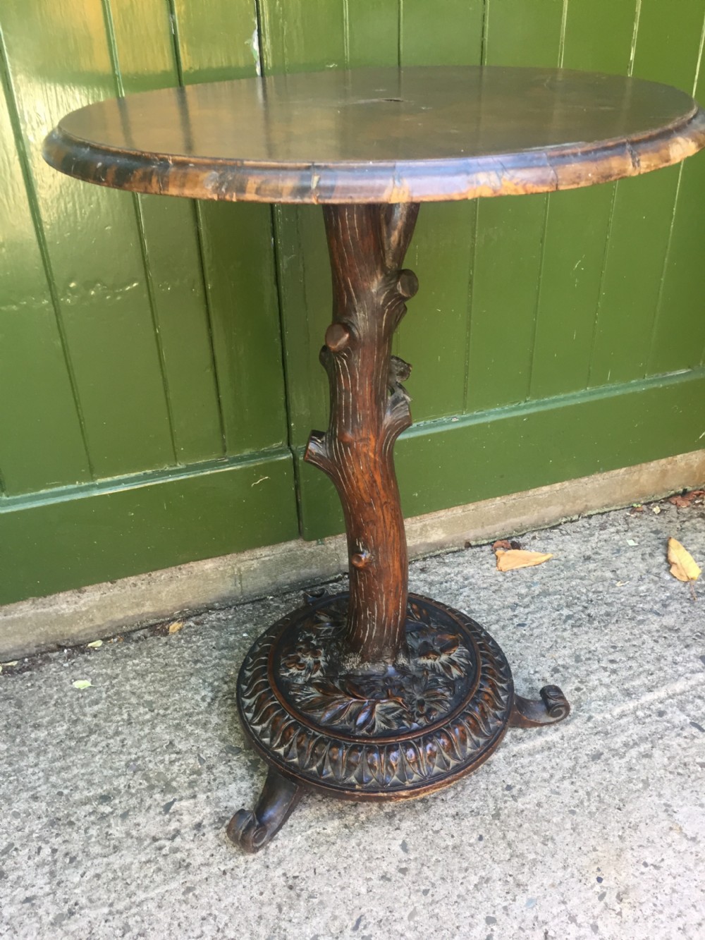 A late nineteenth-century dark brown linden wood side table featuring a circular top supported by a carved tree-trunk stem and a foliage-adorned tripod base. View III
