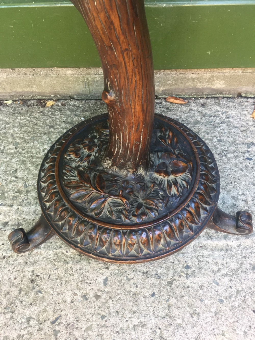 A late nineteenth-century dark brown linden wood side table featuring a circular top supported by a carved tree-trunk stem and a foliage-adorned tripod base. View V
