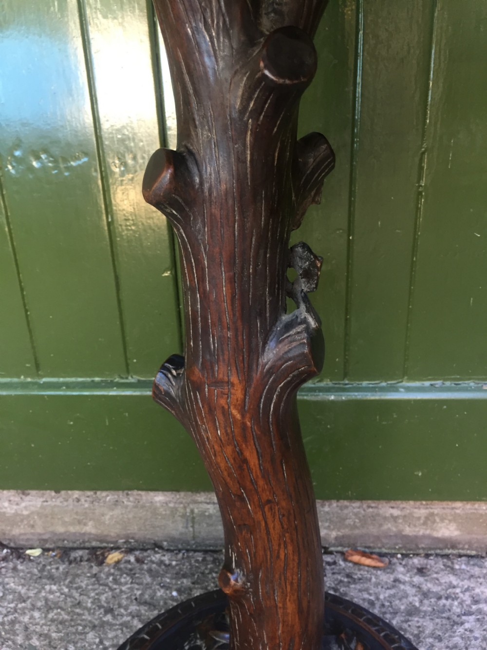 A late nineteenth-century dark brown linden wood side table featuring a circular top supported by a carved tree-trunk stem and a foliage-adorned tripod base. View VI