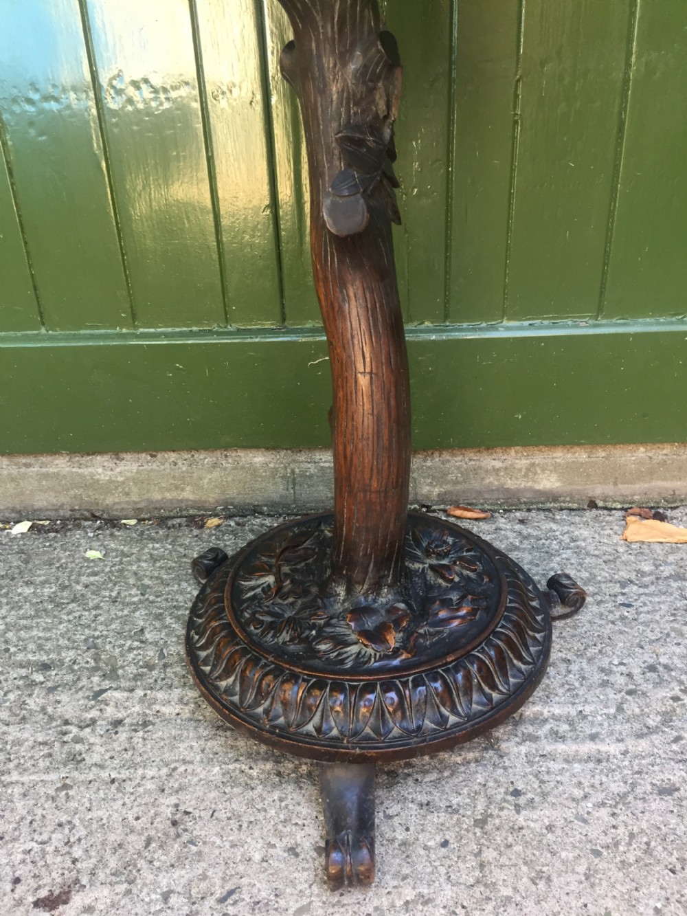 A late nineteenth-century dark brown linden wood side table featuring a circular top supported by a carved tree-trunk stem and a foliage-adorned tripod base. View VII