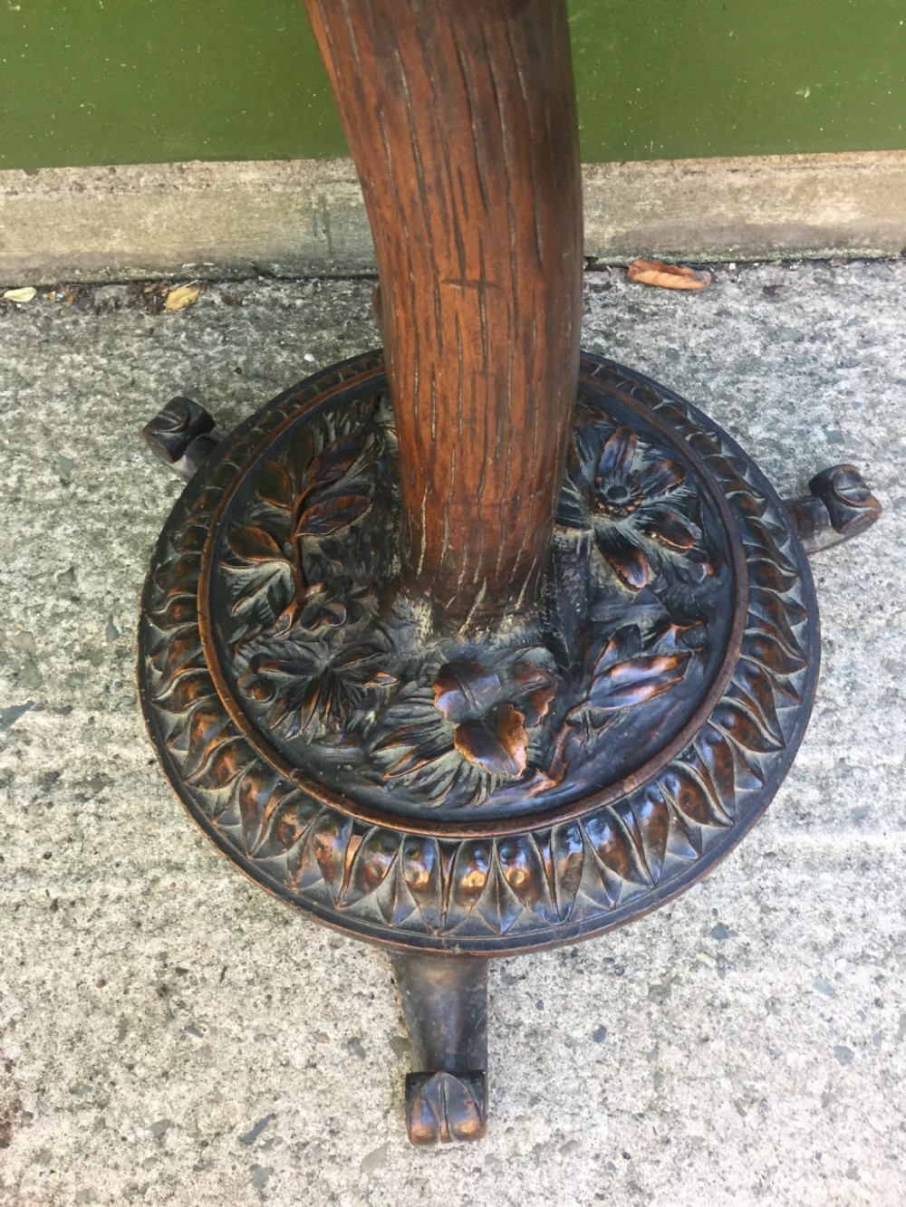A late nineteenth-century dark brown linden wood side table featuring a circular top supported by a carved tree-trunk stem and a foliage-adorned tripod base. View VIII