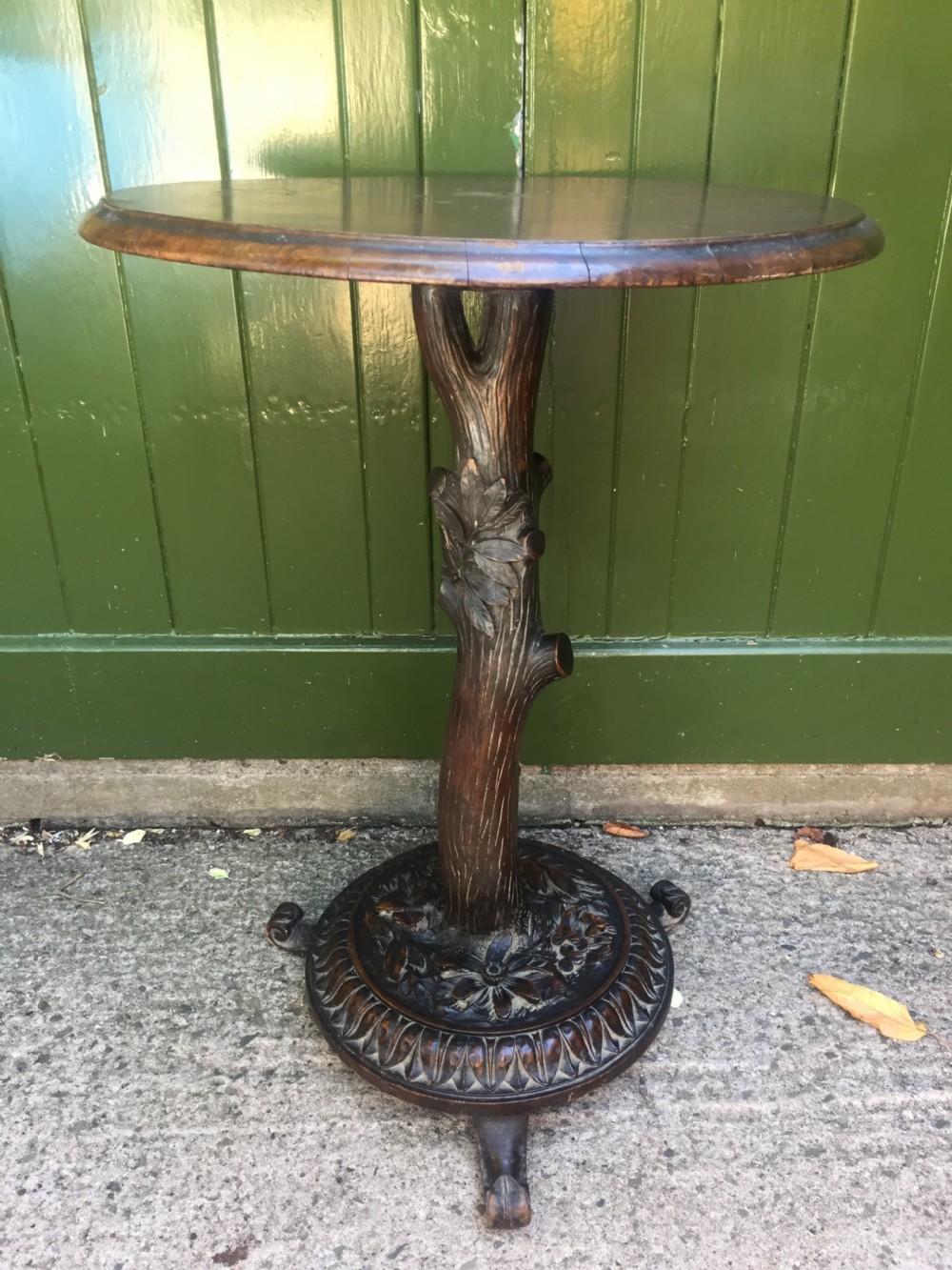 A late nineteenth-century dark brown linden wood side table featuring a circular top supported by a carved tree-trunk stem and a foliage-adorned tripod base. View XIV