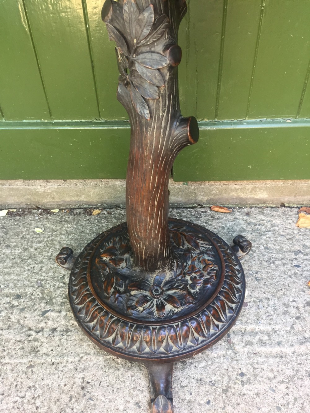 A late nineteenth-century dark brown linden wood side table featuring a circular top supported by a carved tree-trunk stem and a foliage-adorned tripod base. View XV