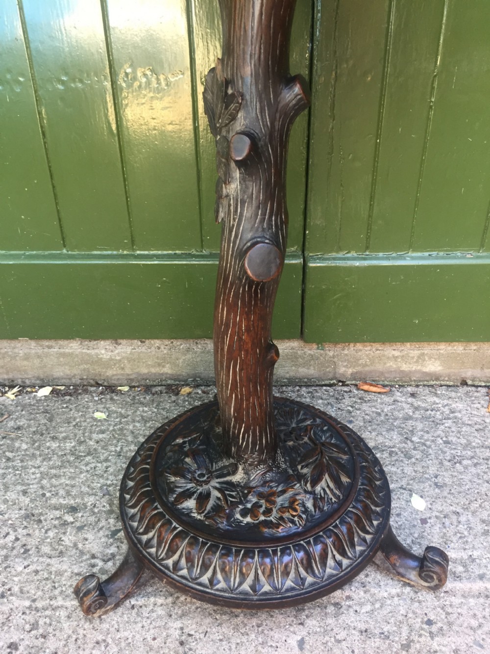 A late nineteenth-century dark brown linden wood side table featuring a circular top supported by a carved tree-trunk stem and a foliage-adorned tripod base. View XVI