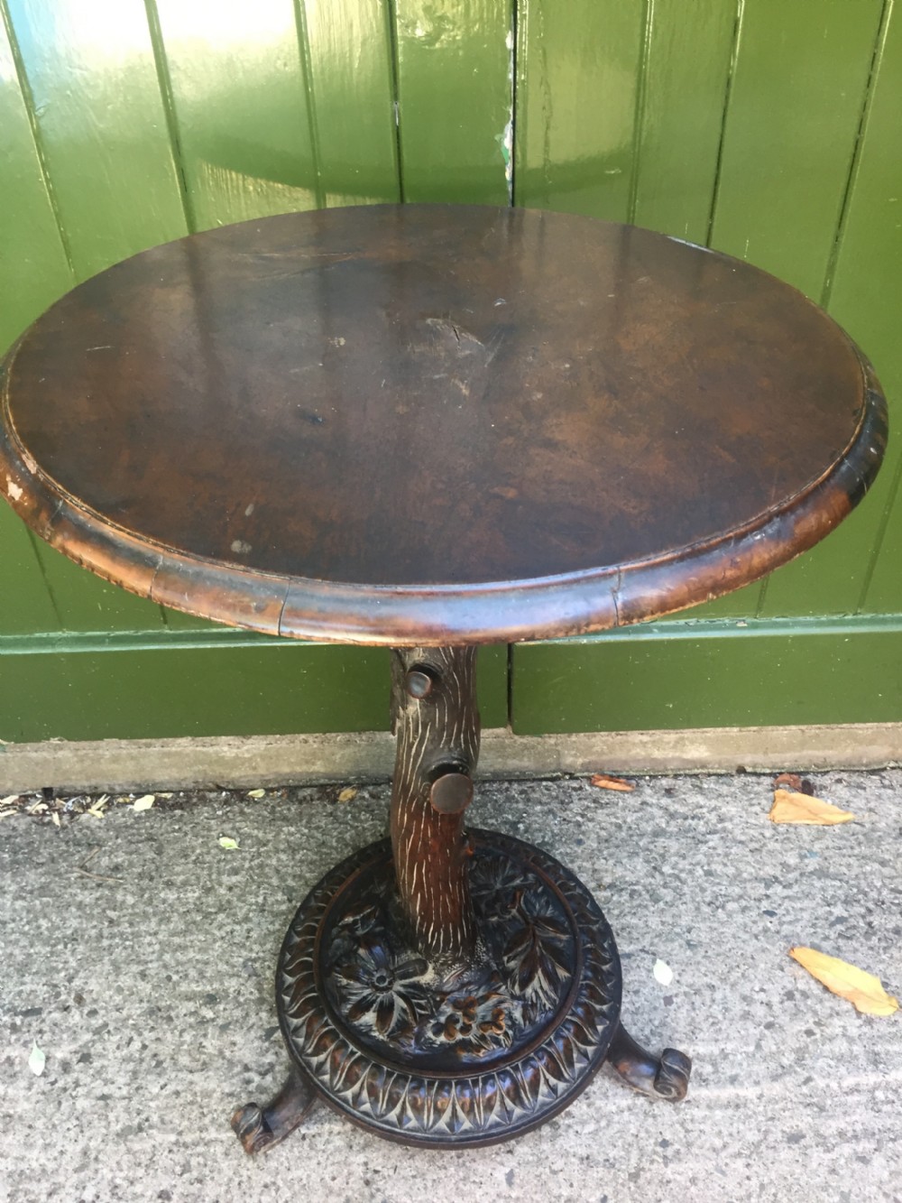 A late nineteenth-century dark brown linden wood side table featuring a circular top supported by a carved tree-trunk stem and a foliage-adorned tripod base. View XVII