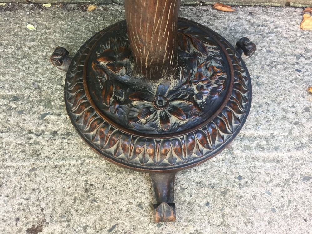 A late nineteenth-century dark brown linden wood side table featuring a circular top supported by a carved tree-trunk stem and a foliage-adorned tripod base. View XIX