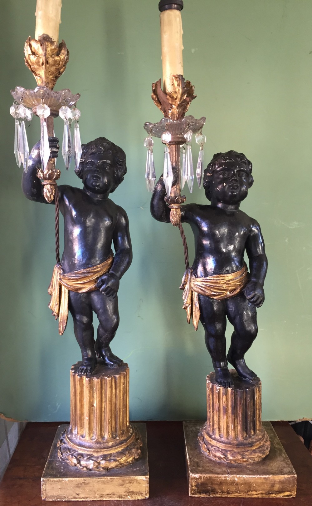 Pair of early C19th Italian carved wood amorini or cherubs modelled as lamps raised on truncated fluted column bases.