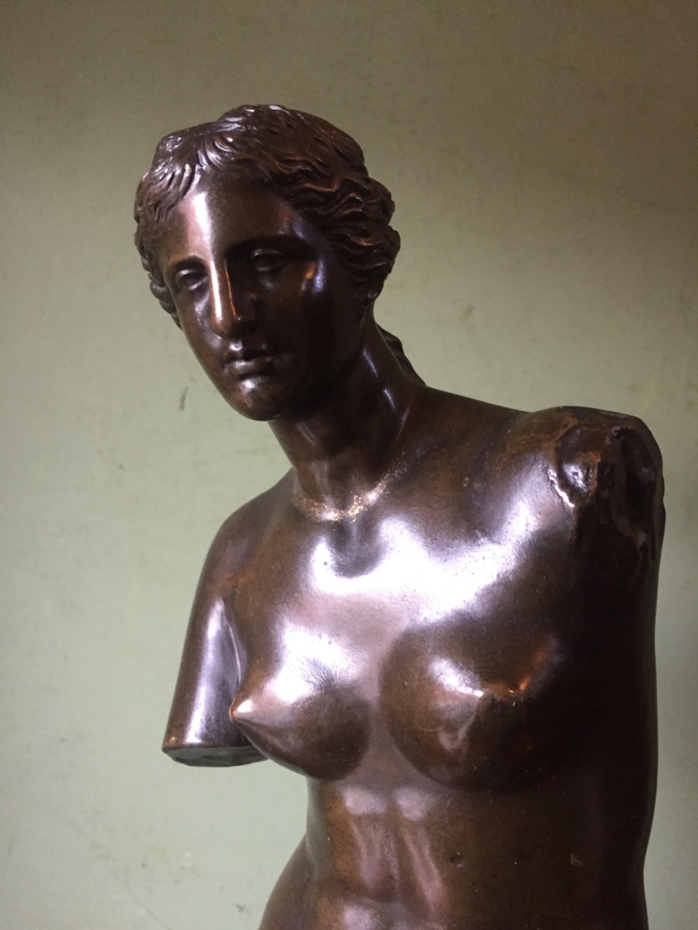 A late nineteenth-century dark bronze sculpture of the armless Venus de Milo standing on an integrated rectangular base. View VIII