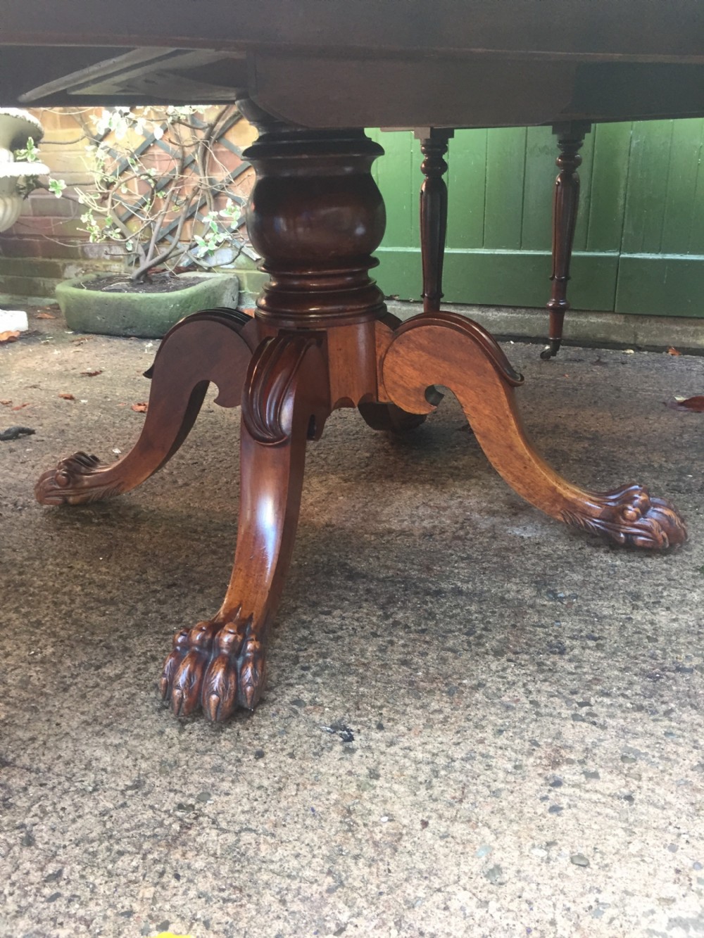 An early nineteenth-century George IV Irish mahogany extending dining table featuring a central pedestal base and turned support legs with brass castors. View V