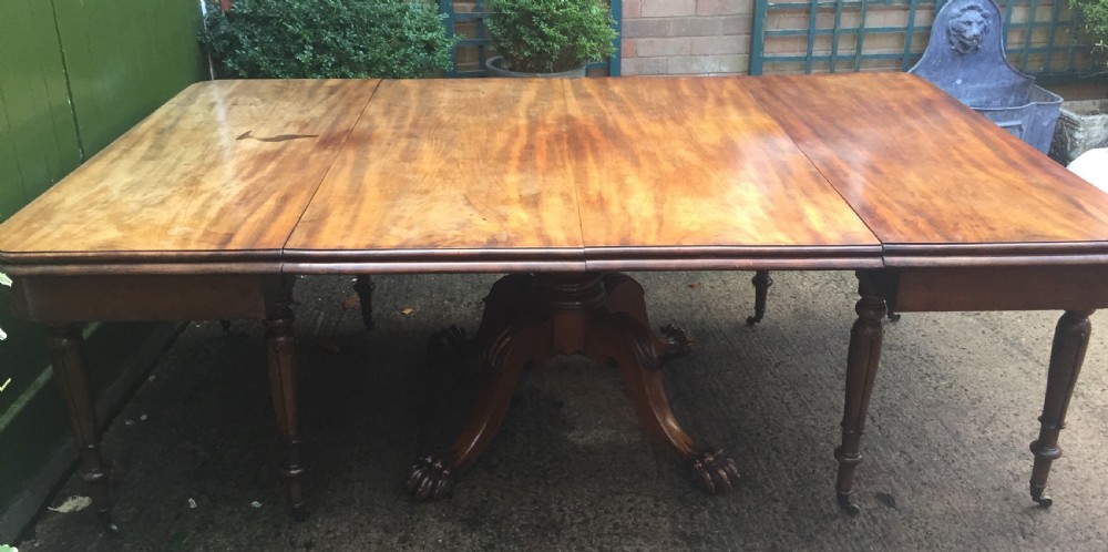 An early nineteenth-century George IV Irish mahogany extending dining table featuring a central pedestal base and turned support legs with brass castors. View XVI