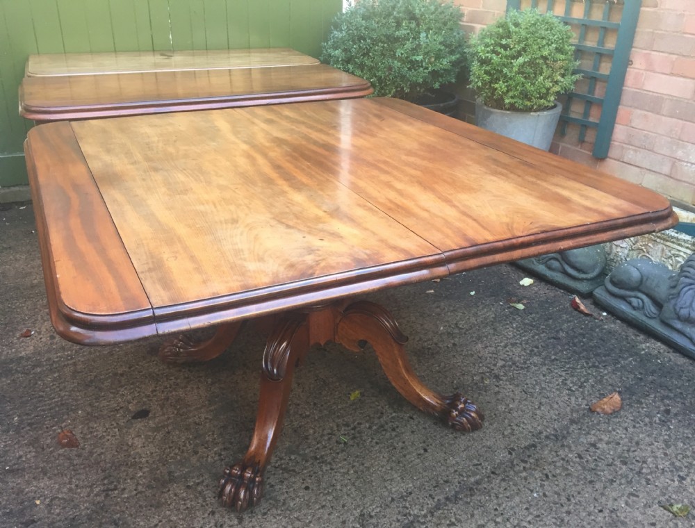 An early nineteenth-century George IV Irish mahogany extending dining table featuring a central pedestal base and turned support legs with brass castors. View XXX