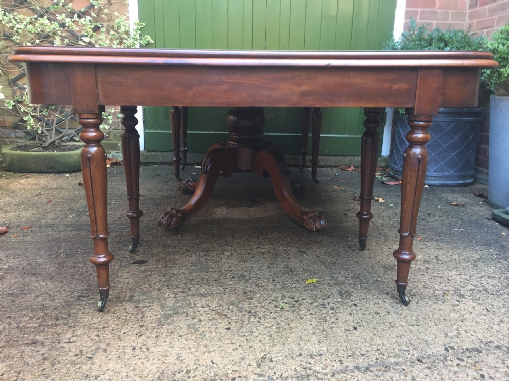 An early nineteenth-century George IV Irish mahogany extending dining table featuring a central pedestal base and turned support legs with brass castors. View XIII